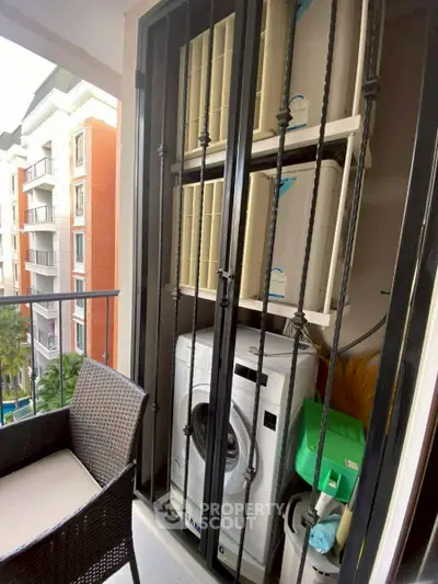 Cozy balcony with washing machine and outdoor seating in modern apartment complex.