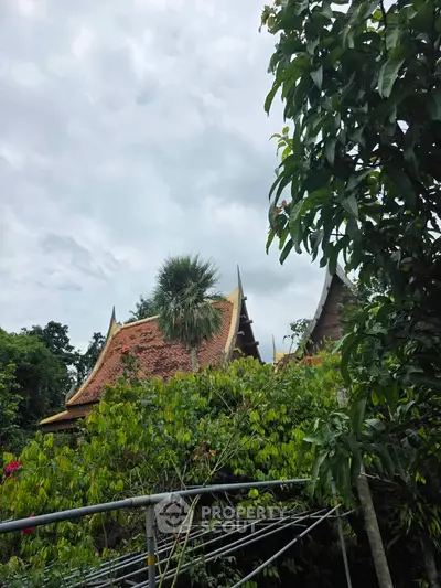 Charming traditional building with ornate roof surrounded by lush greenery, perfect for serene living.