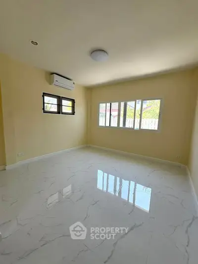 Spacious empty room with glossy marble flooring and large windows for natural light.