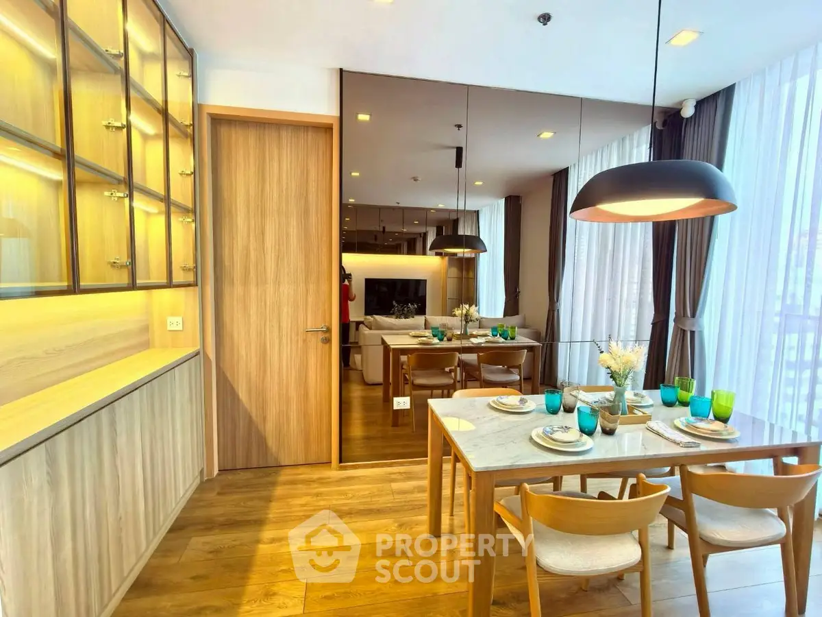 Elegant dining area with wooden flooring and modern lighting in a luxurious apartment.