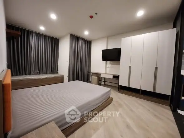 Modern bedroom with sleek design, featuring a large bed, wall-mounted TV, and ample storage space.