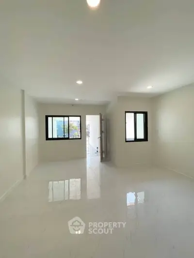 Spacious and bright living room with large windows and modern flooring.
