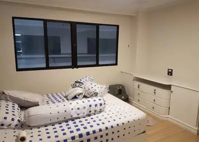 Cozy bedroom with modern decor and ample natural light from large window.