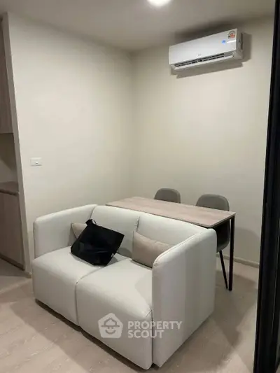 Cozy modern living room with compact sofa and dining table, perfect for small spaces.