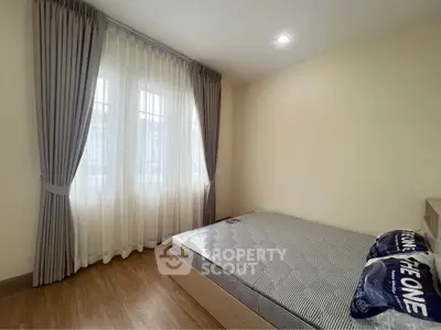 Cozy bedroom with large window and elegant curtains, featuring a comfortable bed and wooden flooring.