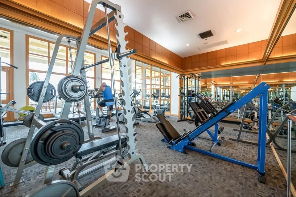 Spacious gym with modern equipment and mirrored walls in luxury real estate property.