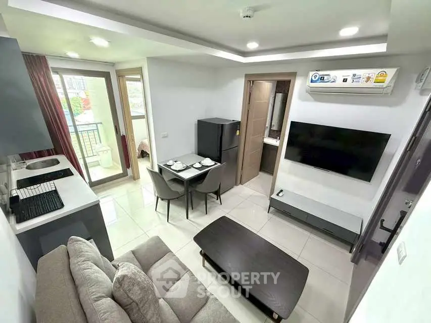 Modern living room with open kitchen and balcony access in stylish apartment.