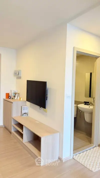 Modern living room with wall-mounted TV and glimpse of bathroom, showcasing sleek design and functionality.