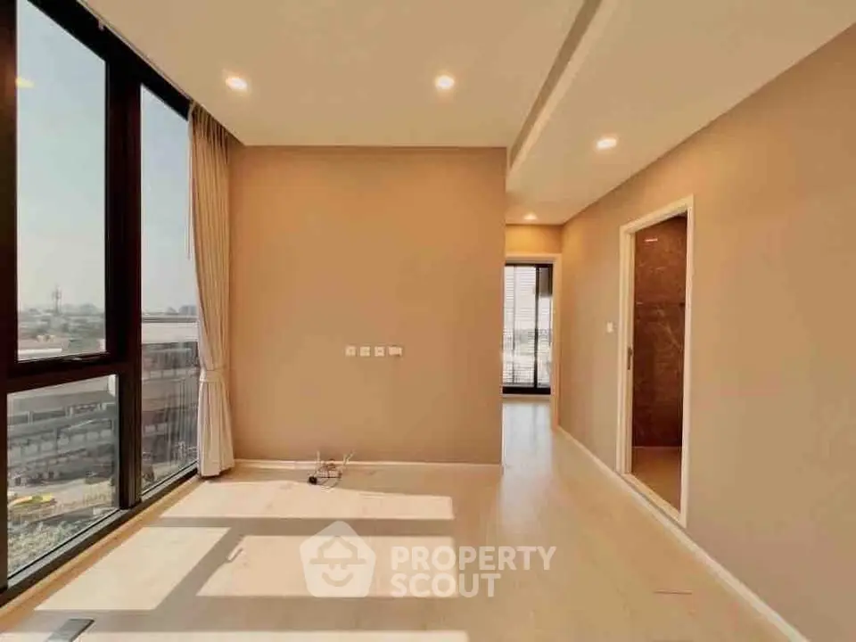 Spacious sunlit living room with large windows and modern design in a high-rise apartment.