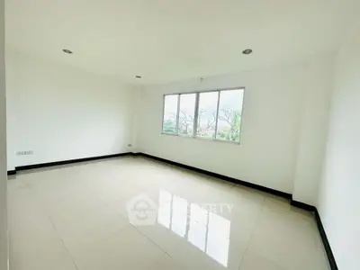 Spacious empty room with large window and glossy tiled floor