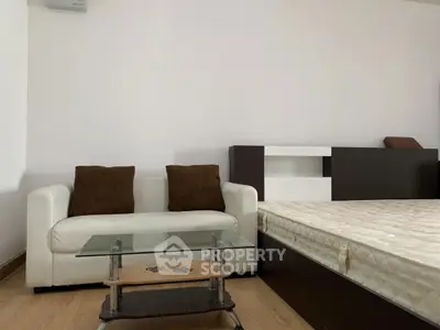 Modern minimalist bedroom with cozy sofa and glass coffee table