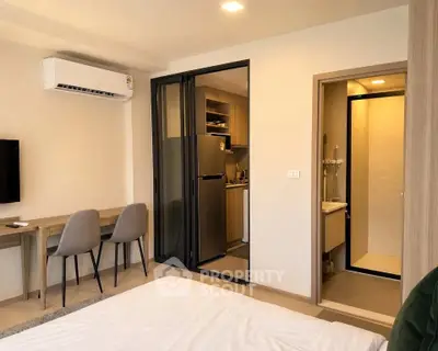 Modern studio apartment with open kitchen and cozy living area, featuring sleek furniture and contemporary design.