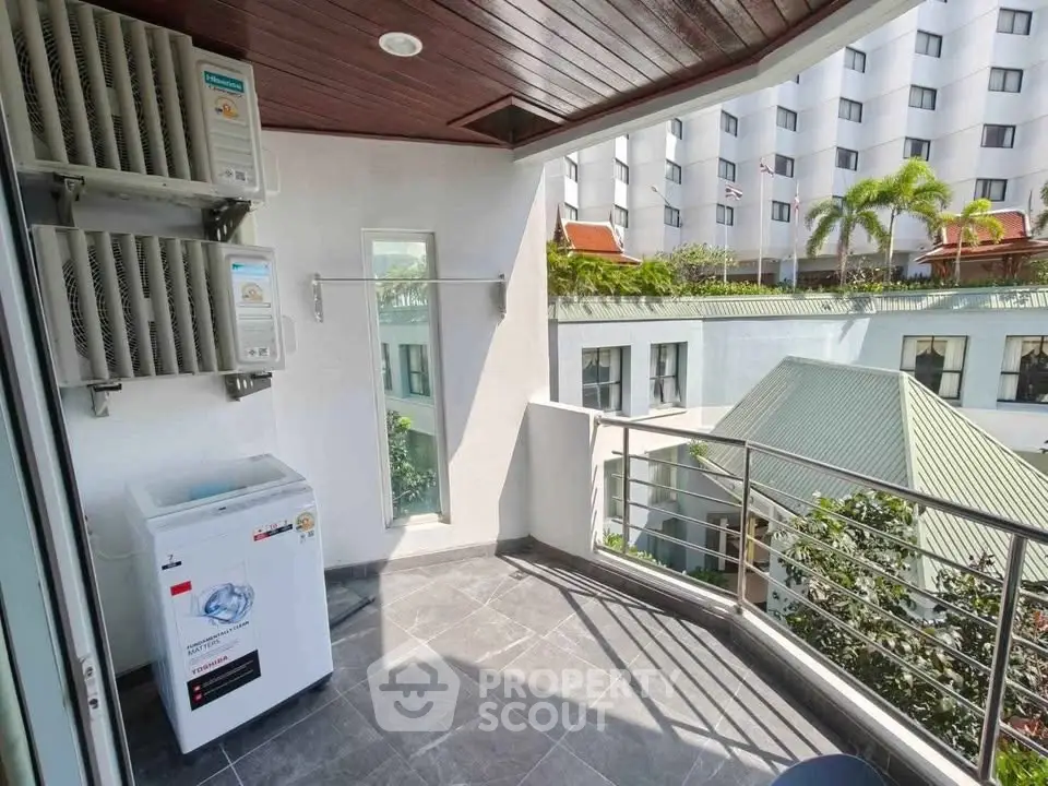 Spacious balcony with modern appliances and scenic view of surrounding buildings.