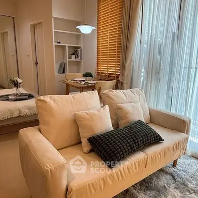 Cozy living room with beige sofa, stylish decor, and natural light through large windows.