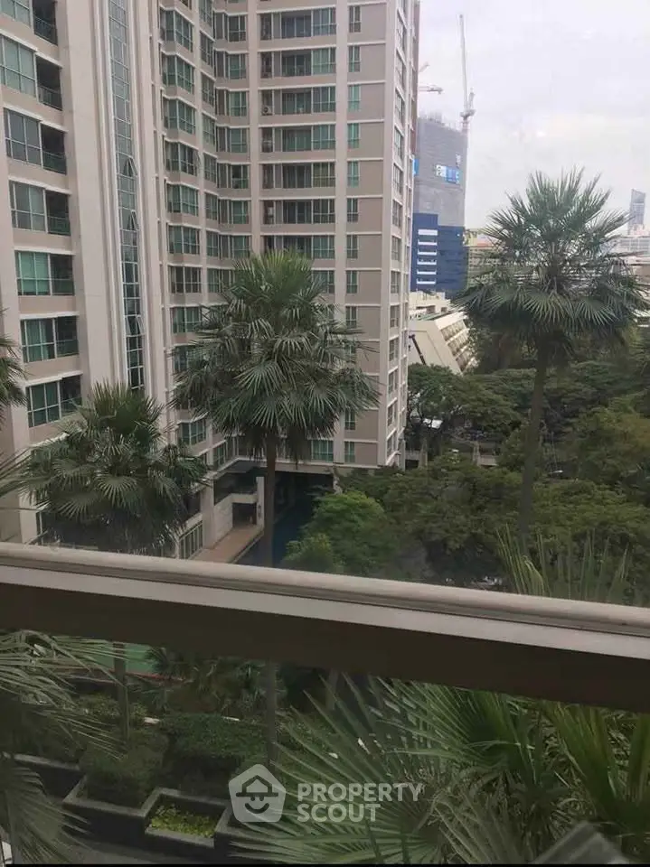 Stunning urban view from high-rise apartment with lush greenery and modern architecture.