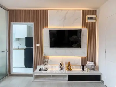 Modern living room with stylish TV wall and open kitchen view, featuring sleek design and contemporary decor.