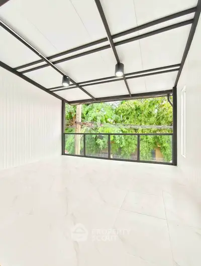 Spacious modern room with large windows and lush greenery view, perfect for serene living.