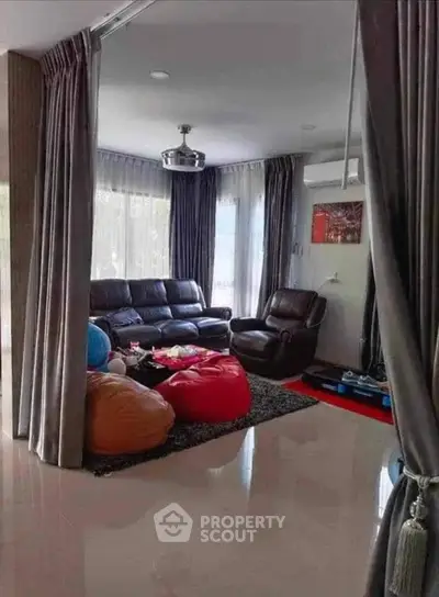 Spacious living room with leather seating and bean bags, perfect for relaxation.