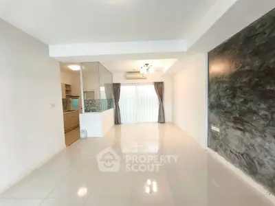 Spacious open-plan living area with modern kitchen and large windows.