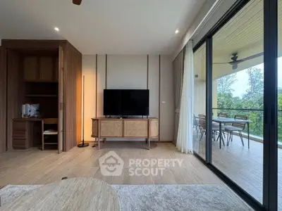 Spacious living room with modern decor and large balcony overlooking lush greenery.