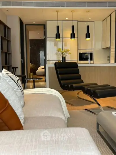 Modern living room with sleek furniture and open kitchen layout, featuring stylish lighting and contemporary design.