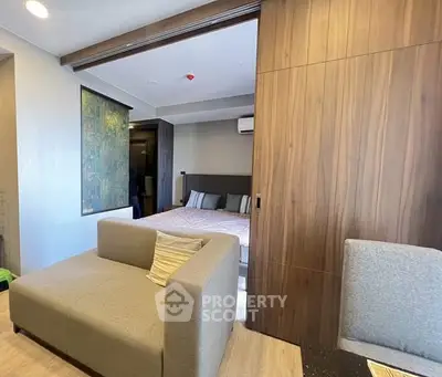 Modern studio apartment with sliding wooden partition and cozy seating area.