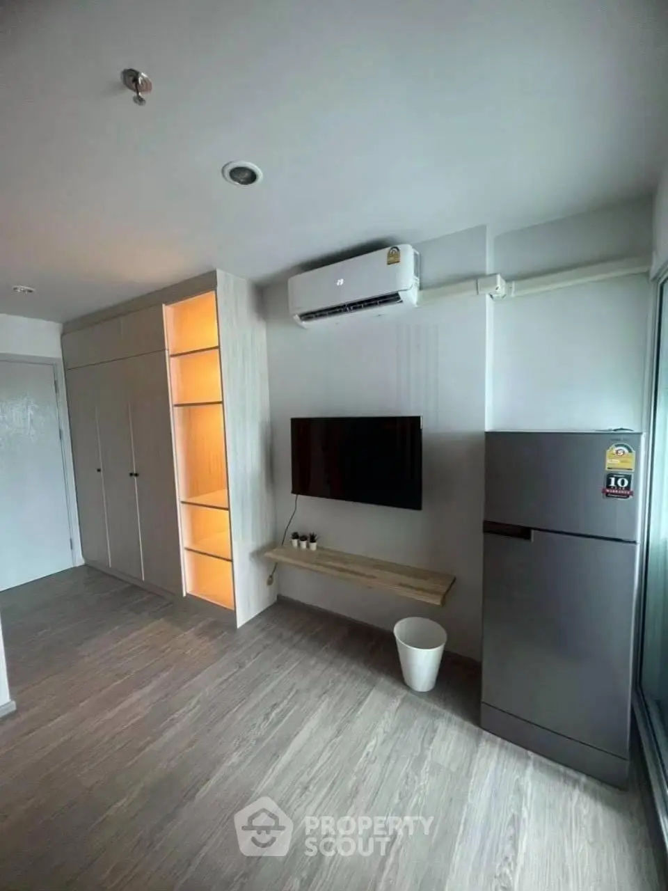 Modern living room with sleek design, featuring built-in storage, air conditioning, and a wall-mounted TV.