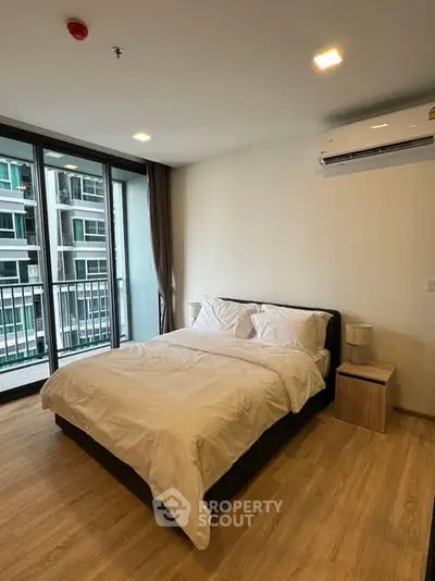 Modern bedroom with large windows and balcony access in a stylish apartment.