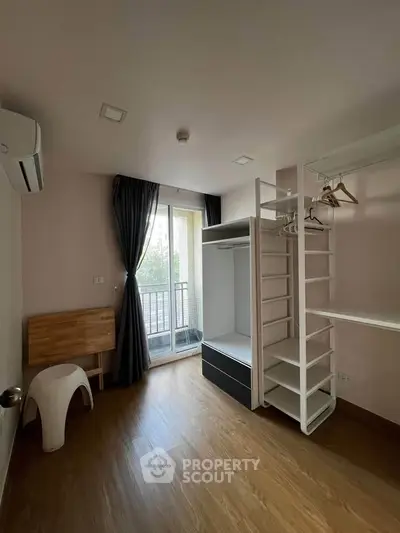 Spacious bedroom with walk-in closet and balcony access in modern apartment.