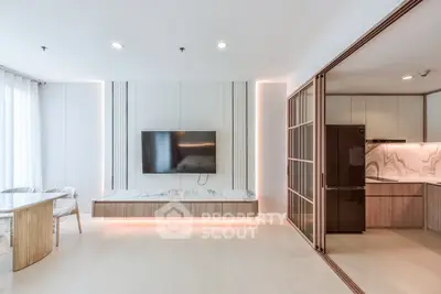 Modern living room with sleek TV setup and open kitchen design