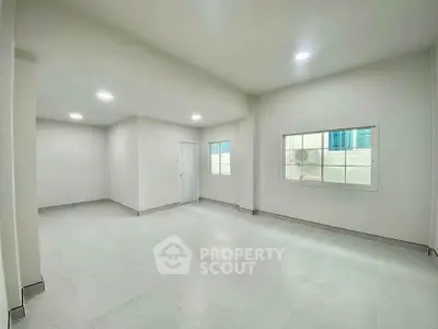 Spacious empty room with large window and modern lighting, perfect for customization.