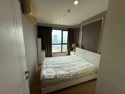 Modern bedroom with large window and city view, featuring sleek furniture and neutral tones.