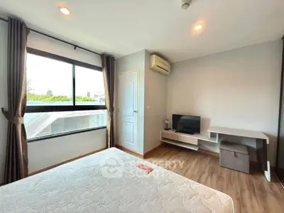 Bright bedroom with large window, modern decor, and wooden flooring