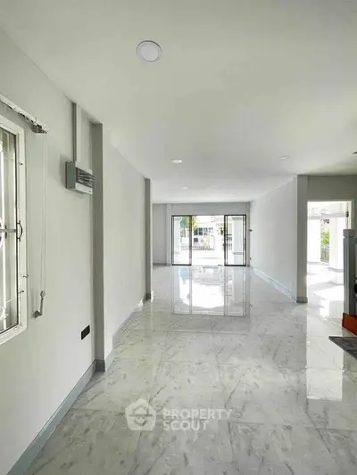 Spacious modern living room with marble flooring and large windows for natural light.