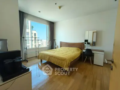 Spacious bedroom with wooden flooring and large window offering city views