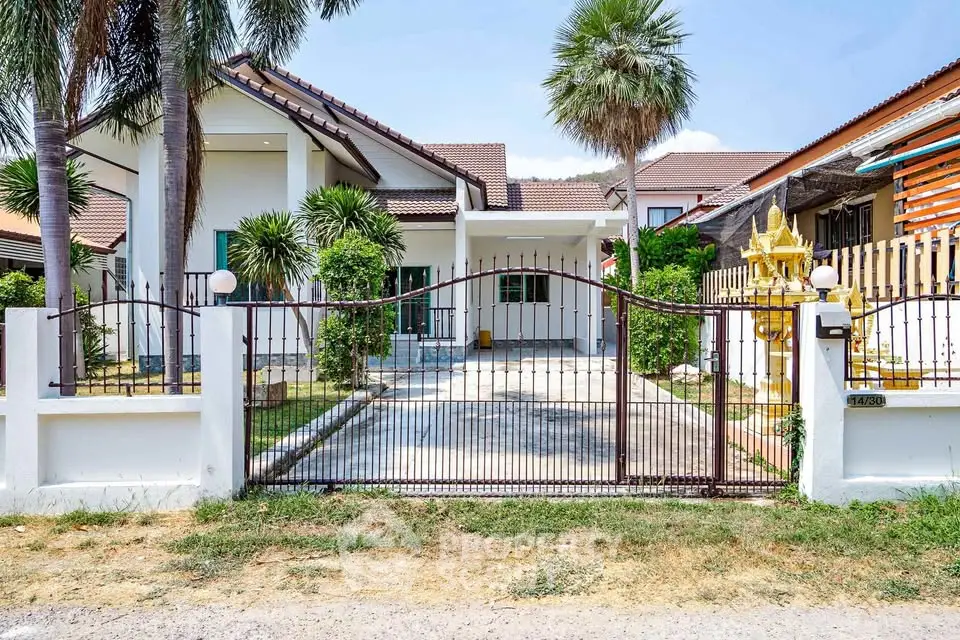 Charming suburban house with gated entrance and lush palm trees, perfect for family living.