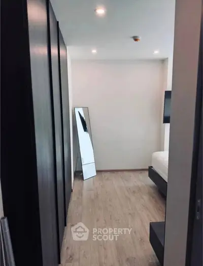 Modern bedroom with sleek design, featuring wooden flooring and a full-length mirror, perfect for urban living.
