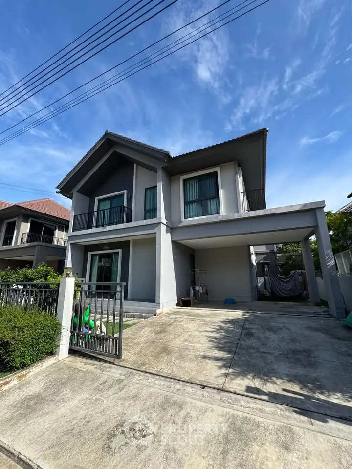 Modern two-story house with driveway and gated entrance in a suburban neighborhood.