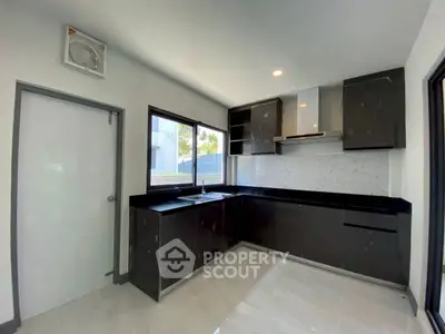 Modern kitchen with sleek black cabinets and large windows