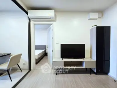 Modern living room with sleek furniture and air conditioning, featuring a TV and stylish decor.