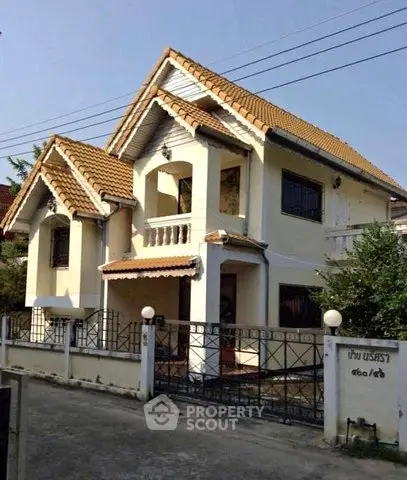 Charming two-story house with tiled roof and gated entrance in a serene neighborhood.