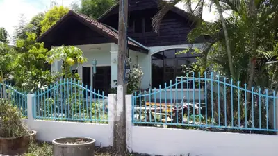Charming single-story house with lush garden and blue fence, perfect for serene living.