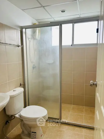 Modern bathroom with glass shower enclosure and tiled walls.