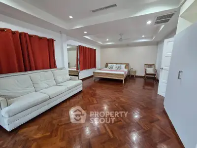Spacious bedroom with elegant wooden flooring and cozy furnishings