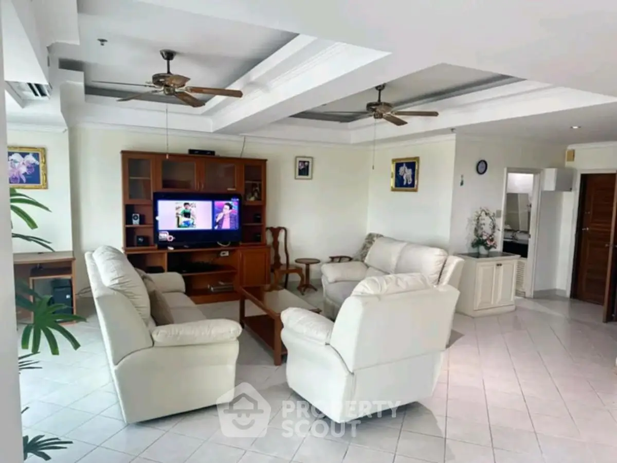 Spacious living room with elegant white sofas and entertainment center, perfect for family gatherings.