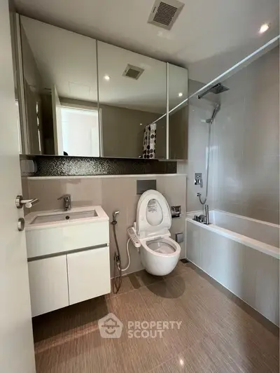 Modern bathroom with sleek fixtures and a spacious bathtub, featuring elegant tile work and a large mirror.