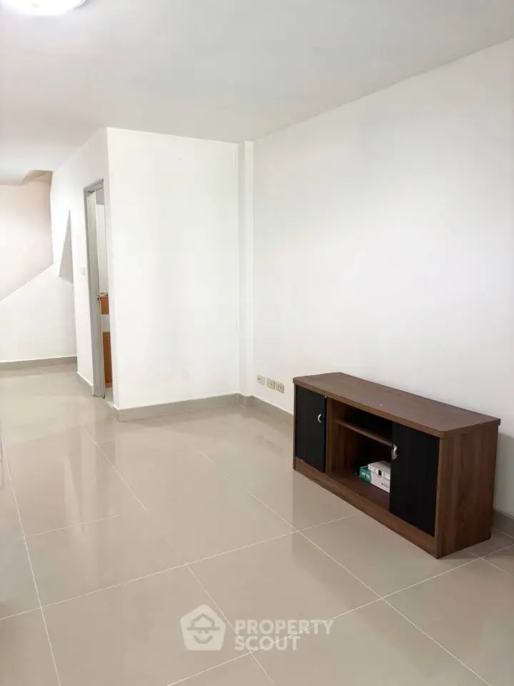Spacious minimalist living area with sleek tile flooring and modern cabinet.