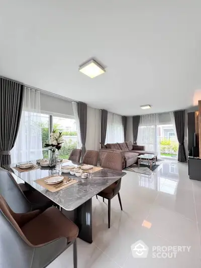 Spacious modern living room with elegant dining area and large windows offering natural light and garden view.