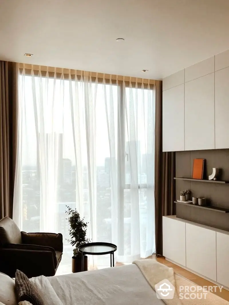 Sunlit modern living room with floor-to-ceiling windows offering a panoramic city view, complemented by minimalist decor and sleek furnishings.