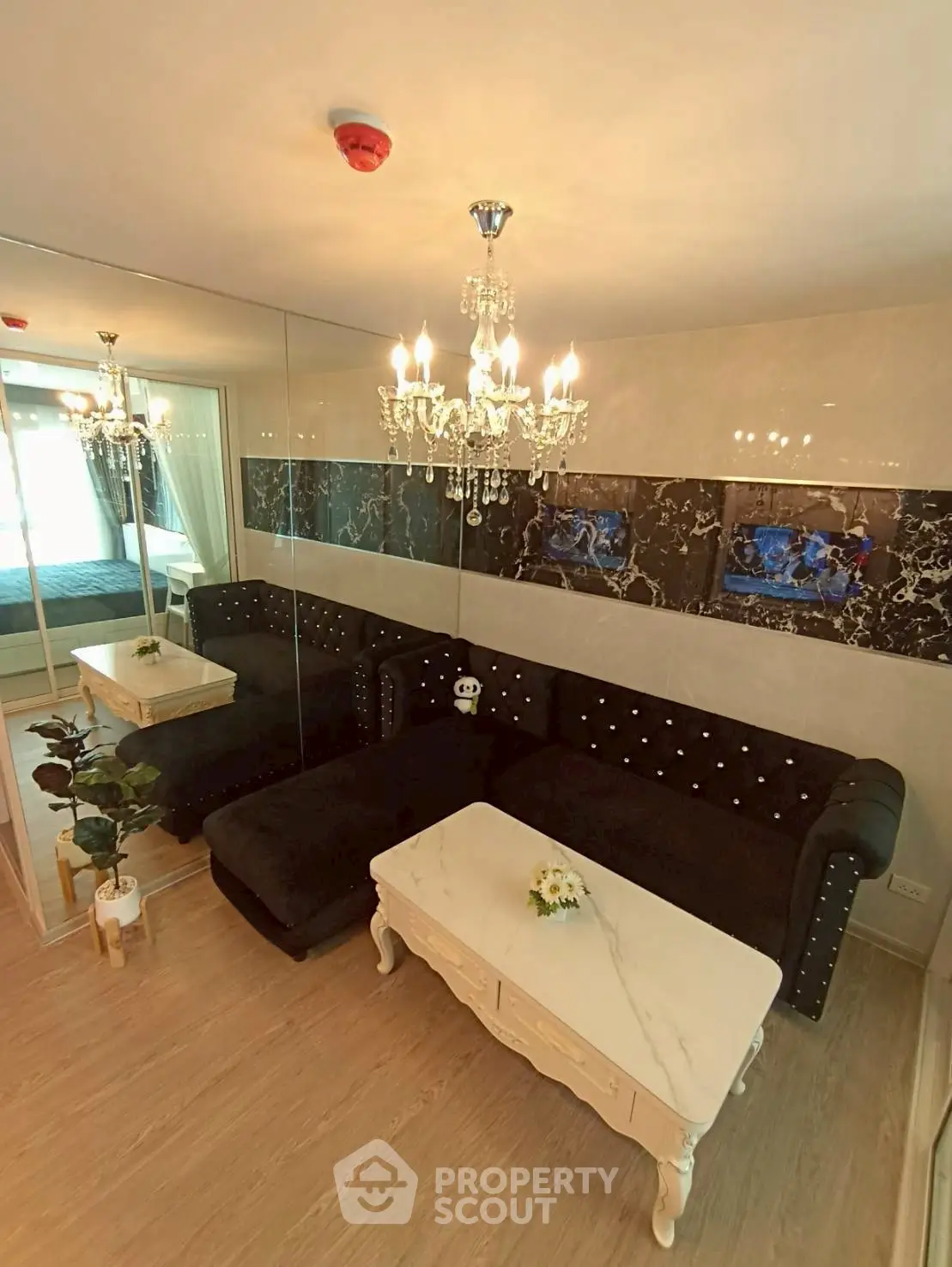 Luxurious living room with elegant chandelier and plush black sofa in modern apartment.